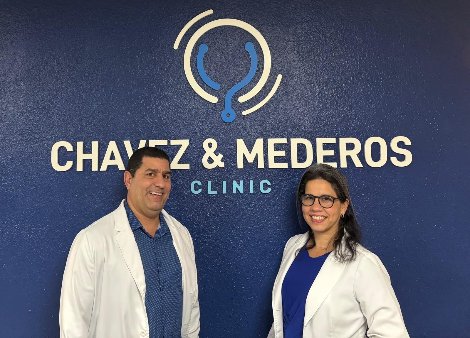 Two Chavez & Mederos providers in white coats in front of the clinic sign